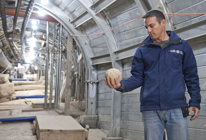 Nachshon Szanton, one of the directors of the Pilgrimage Road excavation, holding a ball of catapults that was apparently used in the battle during the Great Revolt. Photo: Shai Halevi, Israel Antiquities Authority
